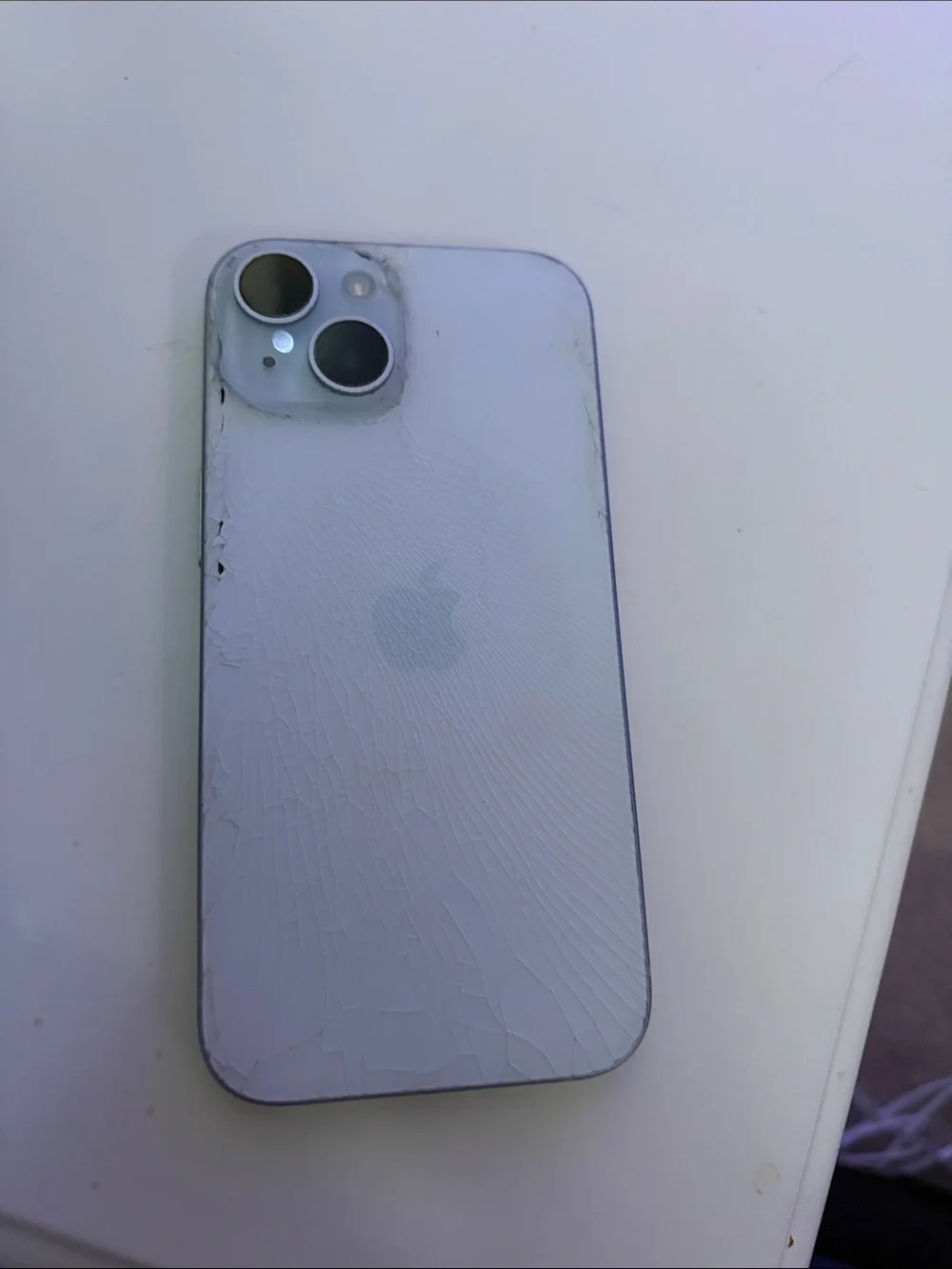 Apple iPhone 15, light blue with clear case.